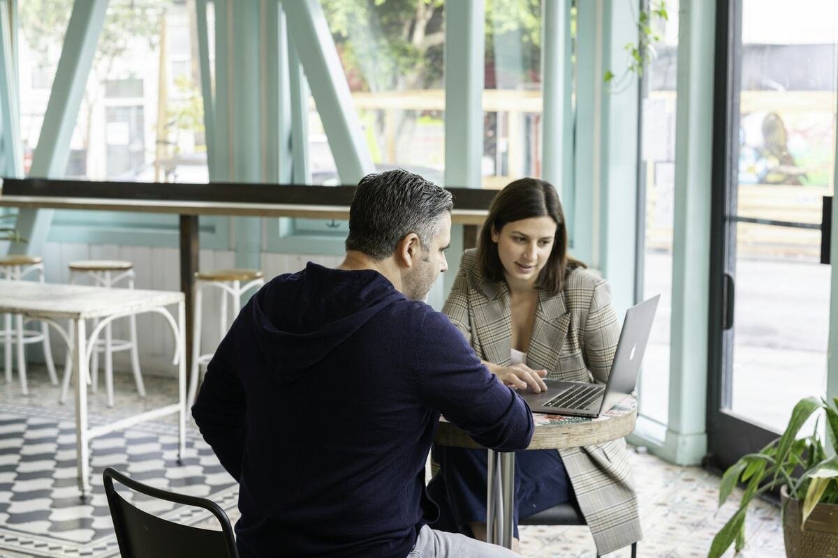 A business owner and a developer reviewing a laptop together at a café table